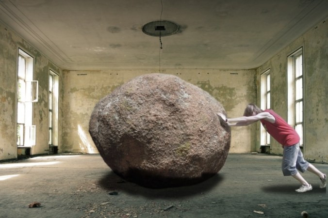 man-pushing-large-rock-in-empty-room